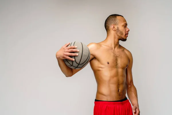 筋肉アフリカ系アメリカ人スポーツマンプレーバスケットボールの下劣な上ライトグレーの背景 — ストック写真