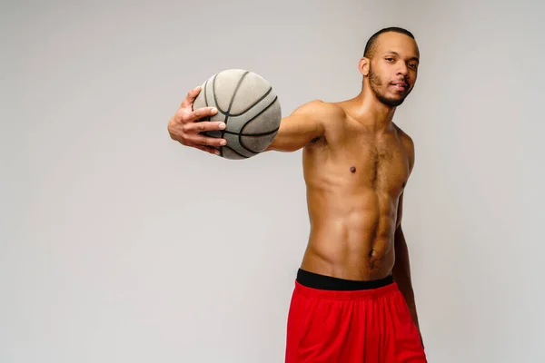 Muscular Africano americano desportista jogar basquete merdoso sobre luz cinza fundo — Fotografia de Stock