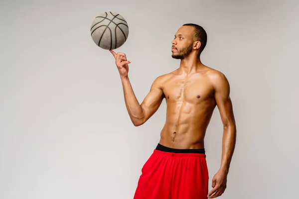 Muscular Africano americano desportista jogar basquete merdoso sobre luz cinza fundo — Fotografia de Stock