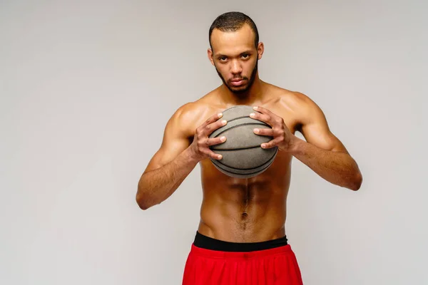 Muscular Africano americano desportista jogar basquete merdoso sobre luz cinza fundo — Fotografia de Stock