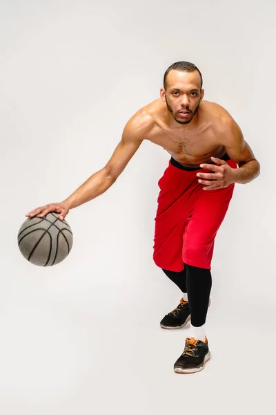 근육질의 미국 스포츠맨, 가벼운 회색 배경 위에서 농구공던지기 — 스톡 사진