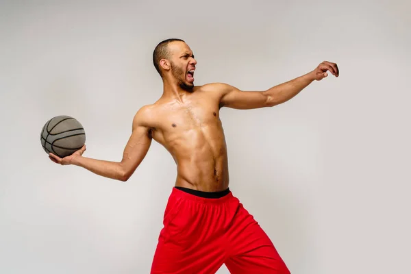 Afrika muskuler olahragawan Amerika bermain basket setengah mati atas latar belakang abu-abu muda — Stok Foto