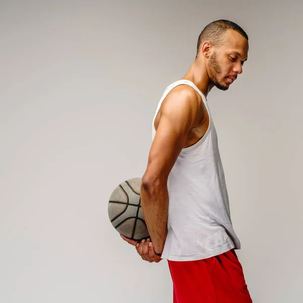 Afrika muskuler olahragawan Amerika bermain basket atas latar belakang abu-abu muda — Stok Foto