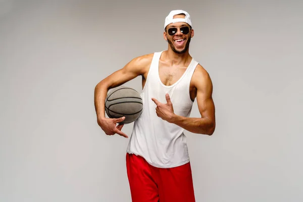 Esportista americano africano muscular jogando basquete sobre fundo cinza claro — Fotografia de Stock