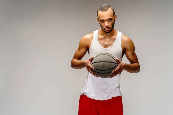 Esportista americano africano muscular jogando basquete sobre fundo cinza claro — Fotografia de Stock