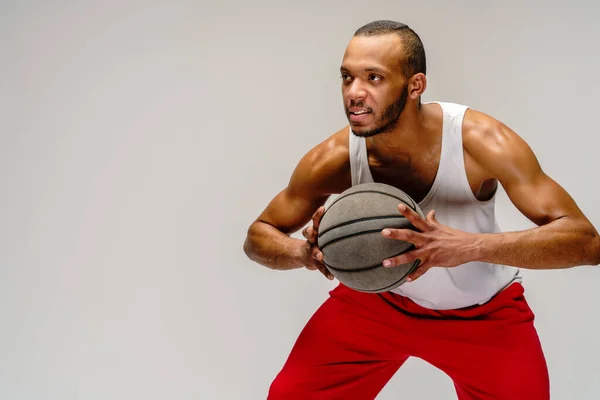 Esportista americano africano muscular jogando basquete sobre fundo cinza claro — Fotografia de Stock