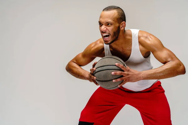 Esportista americano africano muscular jogando basquete sobre fundo cinza claro — Fotografia de Stock