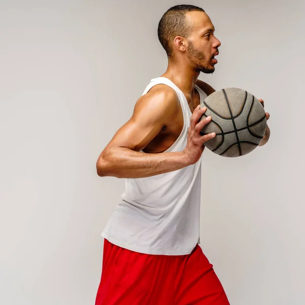 Esportista americano africano muscular jogando basquete sobre fundo cinza claro — Fotografia de Stock