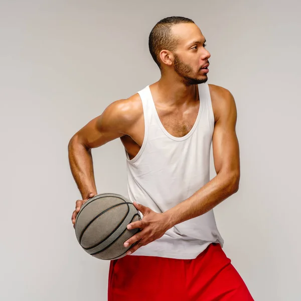 Esportista americano africano muscular jogando basquete sobre fundo cinza claro — Fotografia de Stock