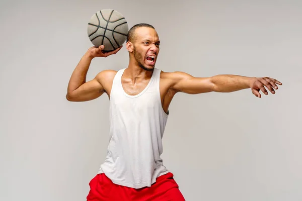 Esportista americano africano muscular jogando basquete sobre fundo cinza claro — Fotografia de Stock