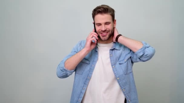 Barbudo joven caucásico hombre usando jeans camisa hablando en el teléfono móvil — Vídeos de Stock