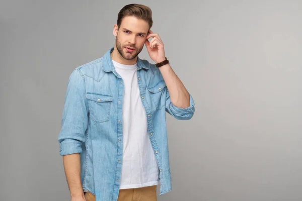 Portret van jonge knappe blanke man in jeans shirt over lichte achtergrond — Stockfoto