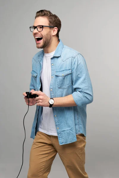 Giovane uomo in jeans casual camicia tenendo joystick o gamepad gioco — Foto Stock