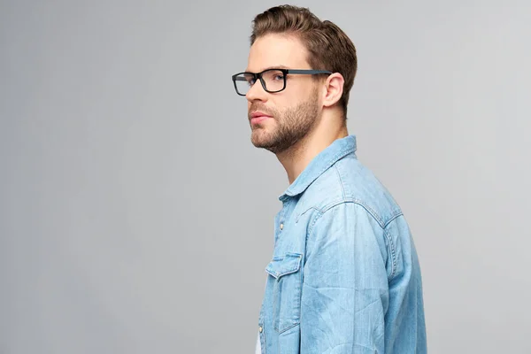 Portrait of young handsome caucasian man in jeans shirt over light background — Stock Photo, Image