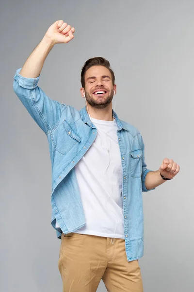 Retrato de cerca de un joven alegre disfrutando escuchando música con un atuendo casual de vaqueros —  Fotos de Stock