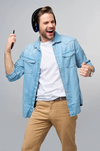 Крупним планом портрет веселого молодого чоловіка, який насолоджується прослуховуванням музики в повсякденному одязі з джинсами — стокове фото