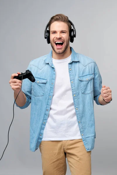 Giovane uomo in jeans casual camicia tenendo joystick o gamepad gioco — Foto Stock