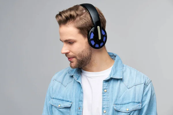 Close up portrait of cheerful young man enjoying listening to music wearing casual jeans outfit — Stock Photo, Image