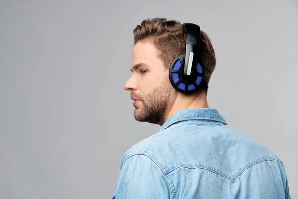 Close up portrait of cheerful young man enjoying listening to music wearing casual jeans outfit — Stock Photo, Image