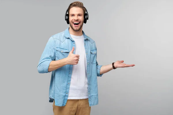 Retrato de cerca de un joven alegre disfrutando escuchando música con un atuendo casual de vaqueros — Foto de Stock