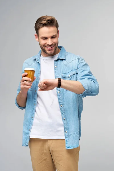 Retrato de joven guapo hombre caucásico en jeans camisa sobre fondo claro sosteniendo taza de café para llevar —  Fotos de Stock