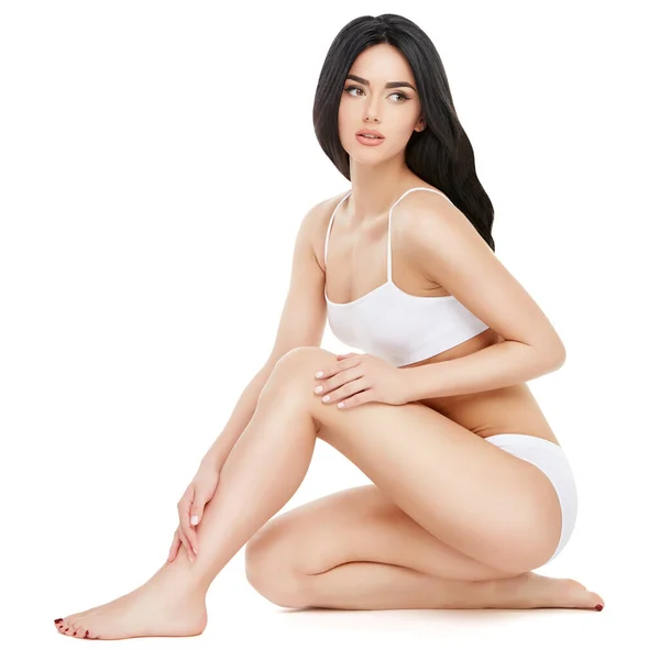 Fitness junge Frau mit einem schönen Körper sitzt auf weißem Hintergrund — Stockfoto