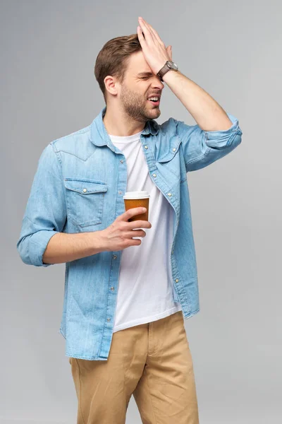 Retrato de joven guapo hombre caucásico en jeans camisa sobre fondo claro sosteniendo taza de café para llevar —  Fotos de Stock