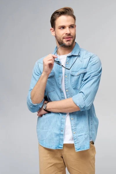 Portrait of young handsome caucasian man in jeans shirt over light background — Stock Photo, Image