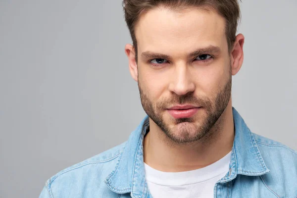 Close-up Portret van jonge knappe blanke man in jeans shirt over lichte achtergrond — Stockfoto