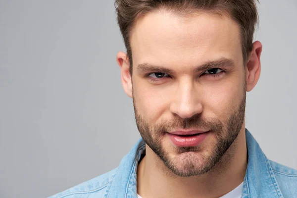 Close-up Portrait of young handsome caucasian man in jeans shirt over light background — Stock Photo, Image