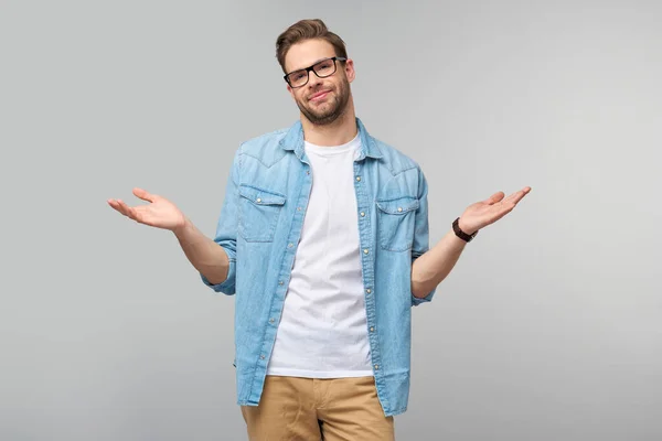 Retrato de jovem sem noção confuso de camisa jeans em pé sobre fundo cinza — Fotografia de Stock