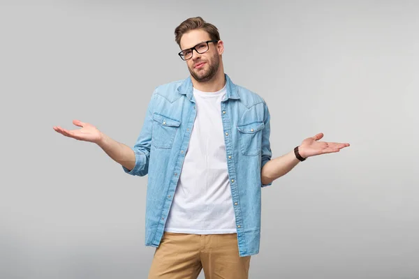 Portrait de jeune homme désorienté en jeans chemise debout sur fond gris — Photo