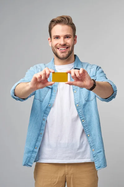 Guapo feliz joven mostrando en blanco banco cor tarjeta de descuento — Foto de Stock