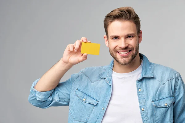 Guapo feliz joven mostrando en blanco banco cor tarjeta de descuento — Foto de Stock