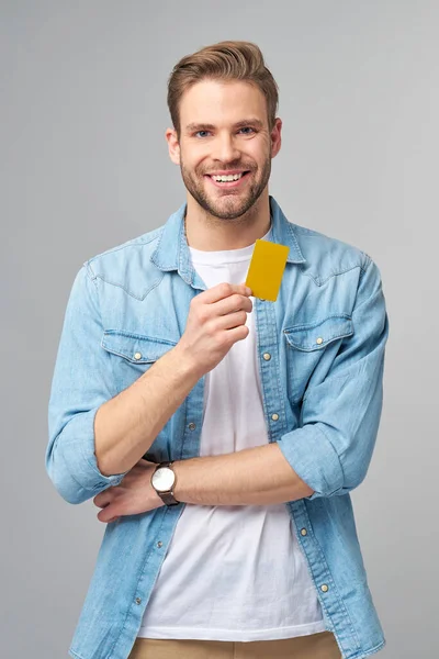 Guapo feliz joven mostrando en blanco banco cor tarjeta de descuento — Foto de Stock