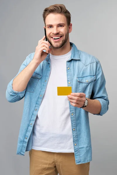 Guapo feliz joven mostrando en blanco banco cor tarjeta de descuento —  Fotos de Stock