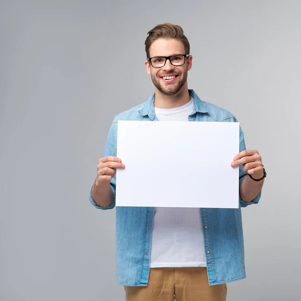 Портрет щасливого красивого молодого чоловіка, який тримає порожню білу картку або підпис на білому тлі — стокове фото