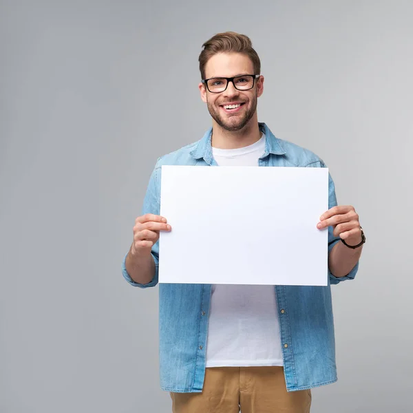 Porträtt av en glad stilig ung man med tomt vitt kort eller underteckna över vit bakgrund — Stockfoto