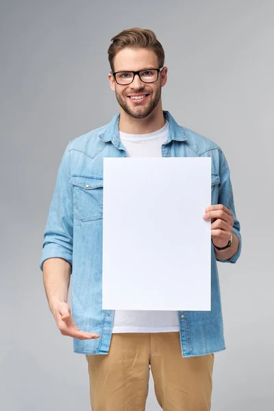 Portrait d'un beau jeune homme heureux tenant carte blanche vierge ou signe sur fond blanc — Photo