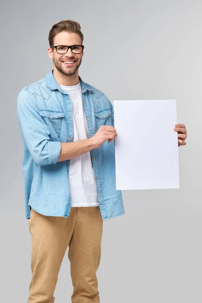 Retrato de um jovem bonito feliz segurando cartão branco em branco ou sinal sobre fundo branco — Fotografia de Stock