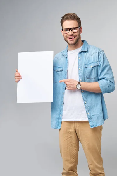 Retrato de um jovem bonito feliz segurando cartão branco em branco ou sinal sobre fundo branco — Fotografia de Stock