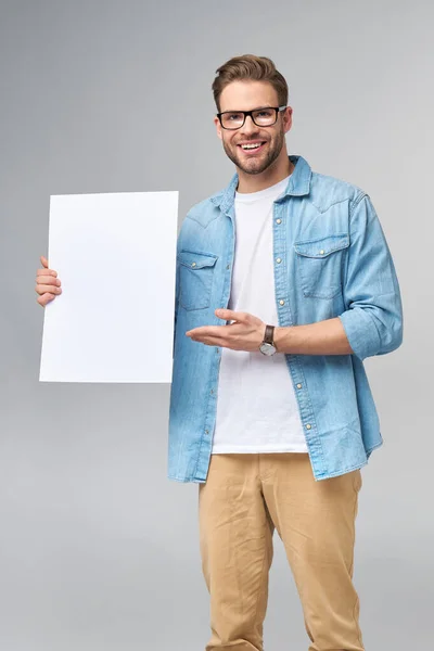 Retrato de un joven guapo feliz sosteniendo tarjeta blanca en blanco o signo sobre fondo blanco —  Fotos de Stock