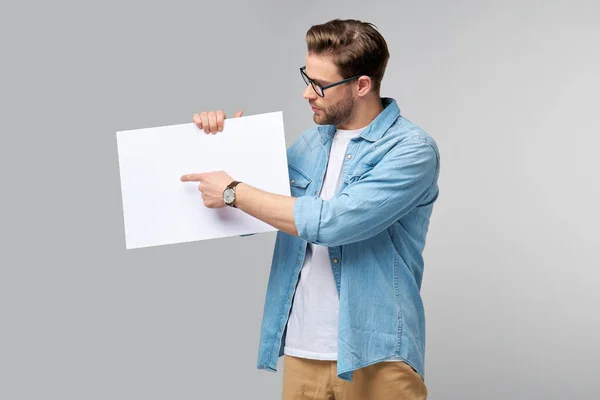 Retrato de un joven guapo feliz sosteniendo tarjeta blanca en blanco o signo sobre fondo blanco — Foto de Stock