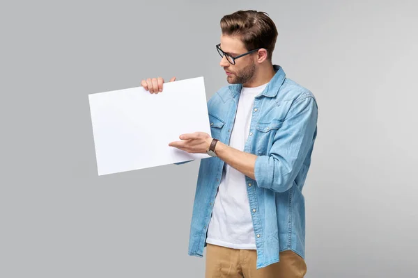 Ritratto di un giovane uomo bello felice che tiene la carta bianca vuota o firma su sfondo bianco — Foto Stock