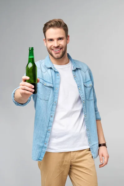 Joven con camisa vaquera Botella de cerveza sobre fondo gris —  Fotos de Stock