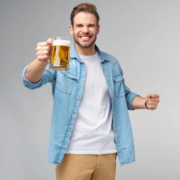 Fiatal férfi gazdaság visel farmer ing kezében üveg sör felett áll szürke háttér — Stock Fotó
