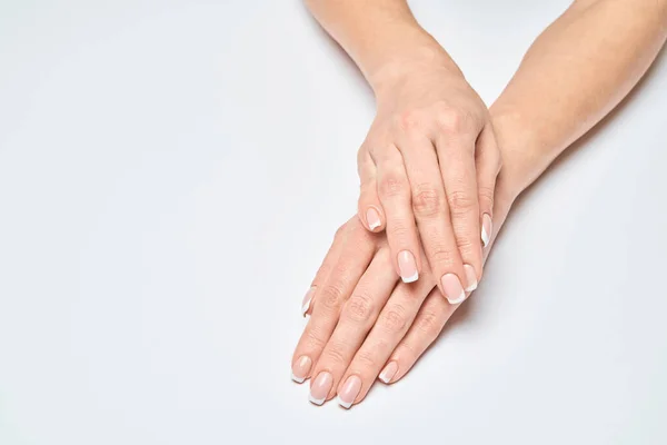 Mãos femininas bonitas com manicure francês sobre fundo cinza claro — Fotografia de Stock