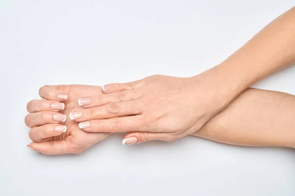 Belle mani femminili con manicure francese su sfondo grigio chiaro — Foto Stock