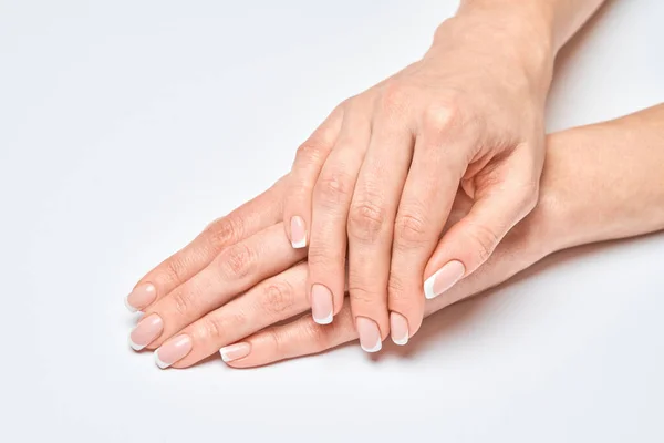 Belle mani femminili con manicure francese su sfondo grigio chiaro — Foto Stock