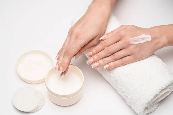 Nahaufnahme einer schönen weiblichen Hand, die Handcreme über grauem Hintergrund aufträgt — Stockfoto